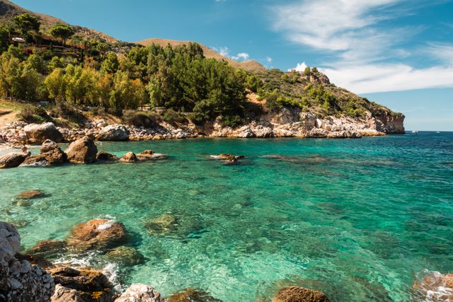Serene coastal view with turquoise waters and rocky cliffs under a bright sky.